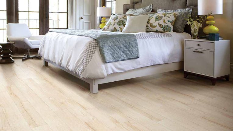 Light toned wood look laminate planks in a bright and airy bedroom